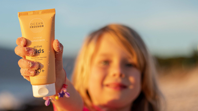 a Girl holding up Ocean Freedom SPF 50+ Kids Active Sunscreen